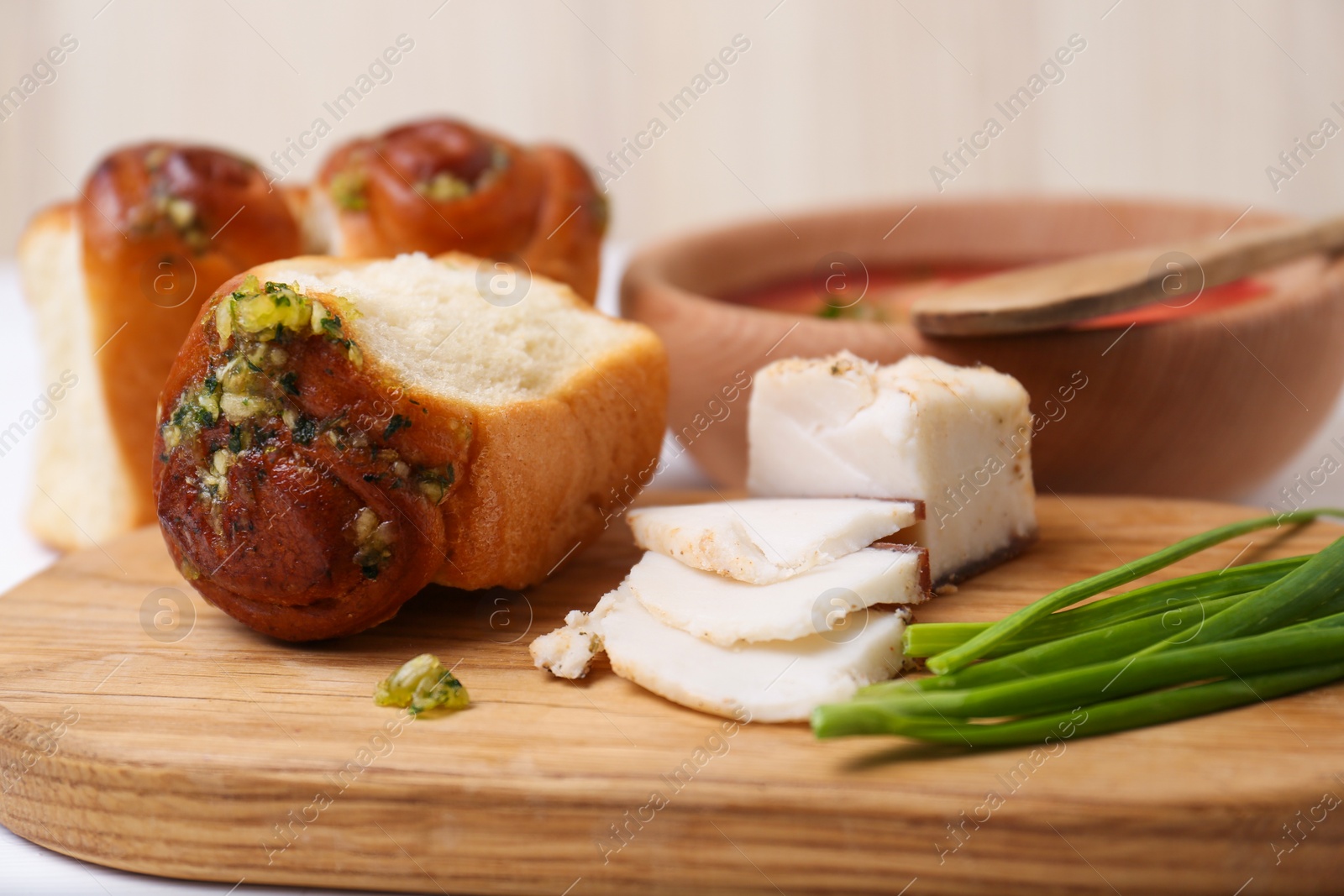 Photo of Delicious pampushky (buns with garlic), green onions and salo served for borsch on table, closeup. Traditional Ukrainian cuisine