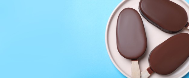 Plate with glazed ice cream bars on light blue background, top view with space for text. Banner design