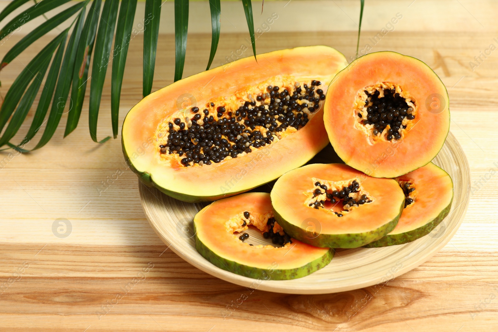 Photo of Plate with fresh juicy cut papayas on wooden background