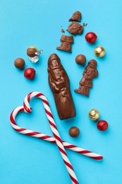 Photo of Flat lay composition with chocolate Santa Claus candies and sweets on light blue background