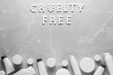 Photo of Text Cruelty Free of pills and personal care products on light marble table, flat lay. Stop animal tests