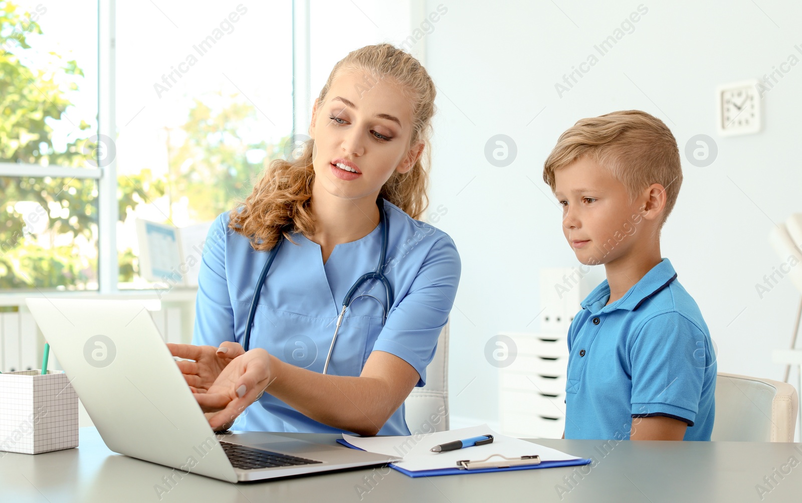 Photo of Female medical assistant explaining physical examination result to child in clinic