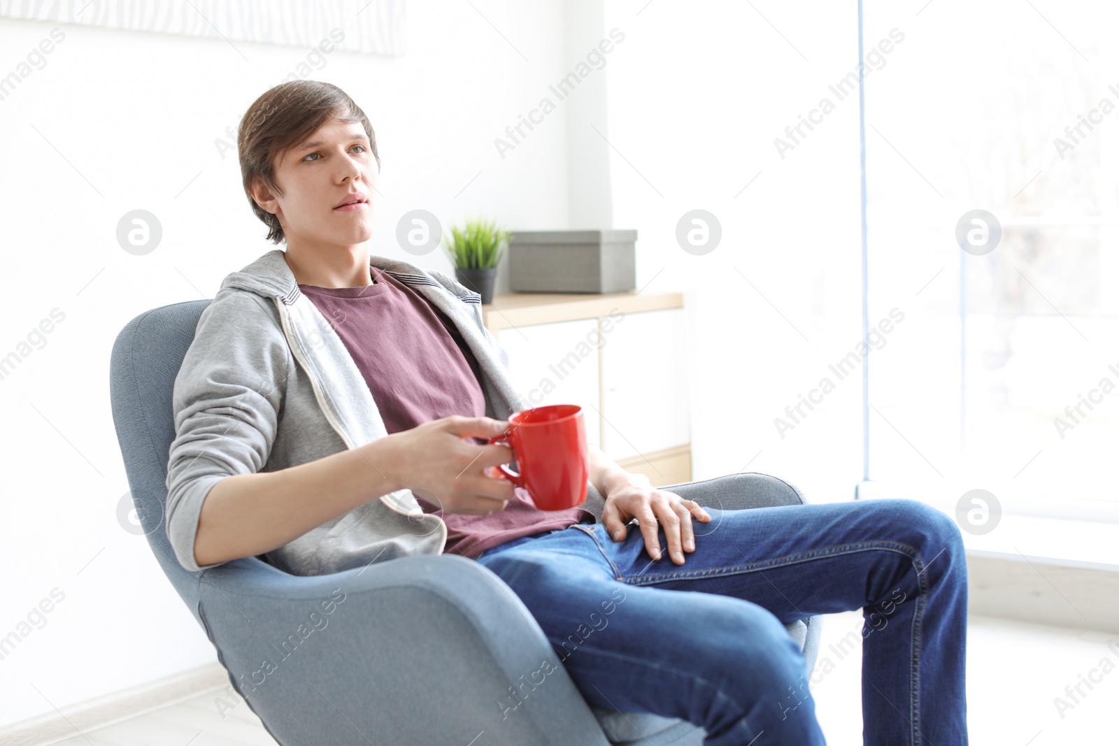 Photo of Portrait of young man drinking coffee in armchair