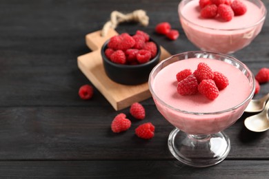 Photo of Delicious raspberry mousse on black wooden table, space for text