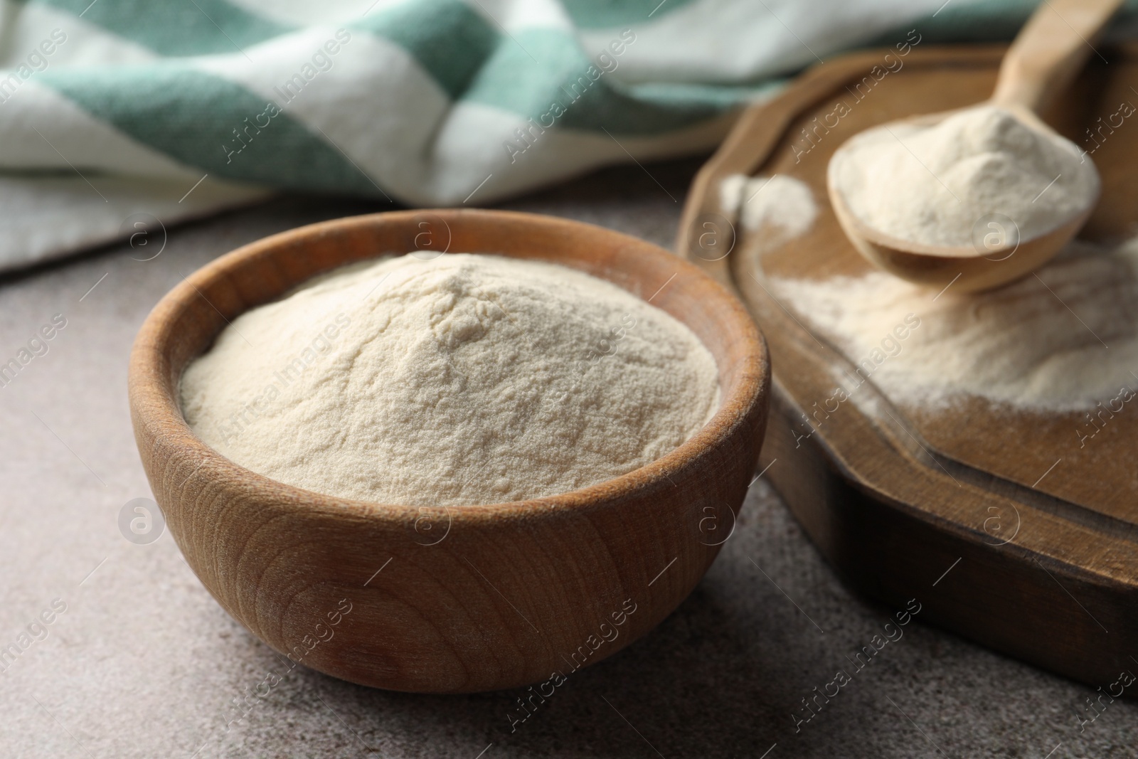 Photo of Bowl and spoon of agar-agar powder on grey table, closeup