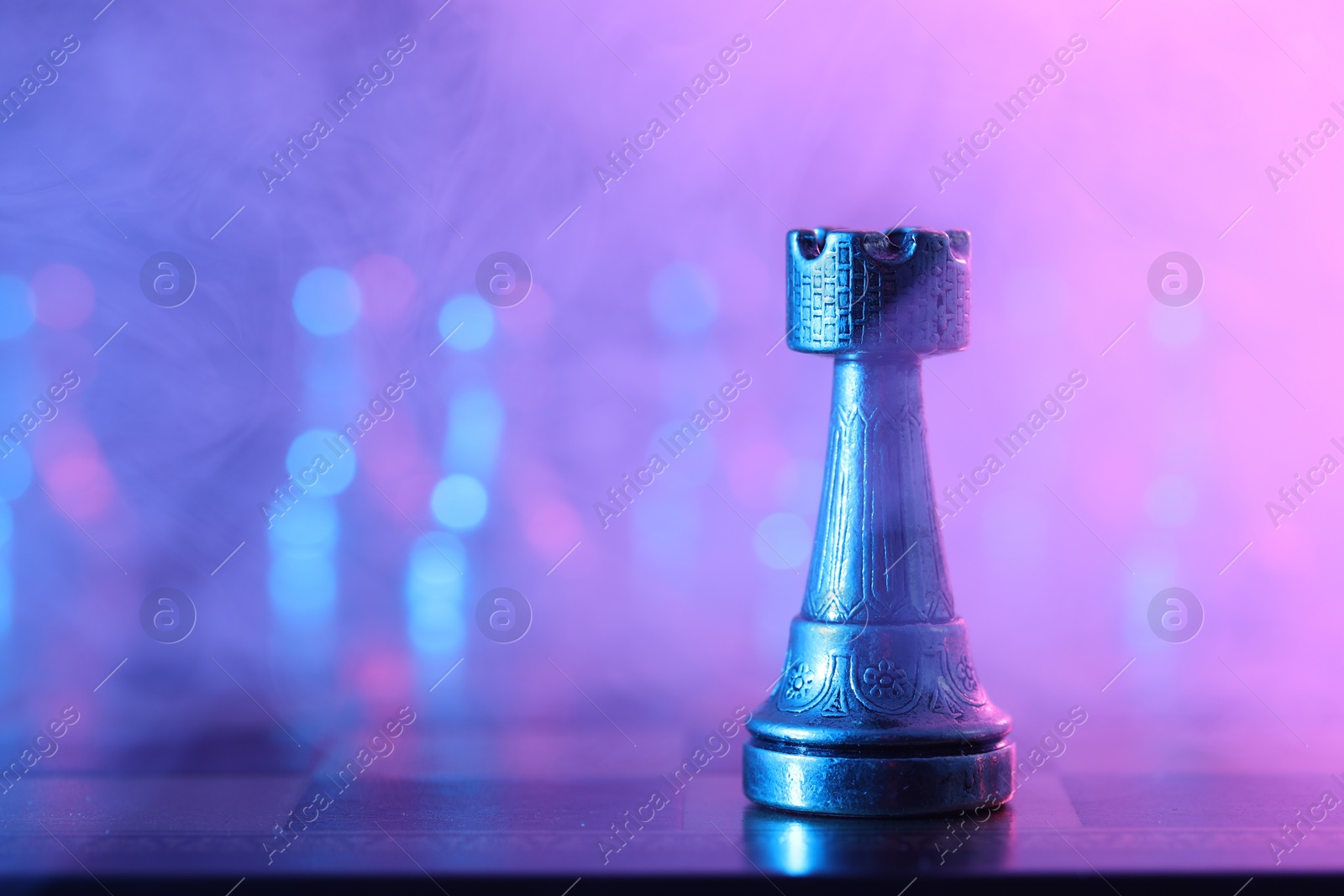 Photo of Rook on chessboard in color light, selective focus. Space for text