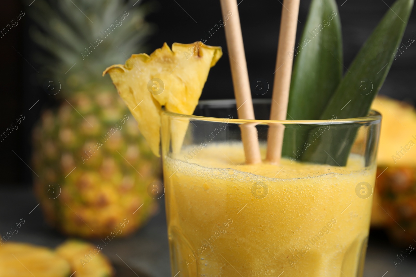 Photo of Tasty pineapple smoothie and fruit on blurred background, closeup