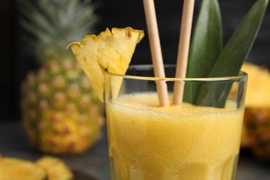 Tasty pineapple smoothie and fruit on blurred background, closeup