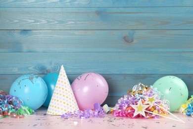 Colorful serpentine streamers and other party accessories on pink wooden table. Space for text