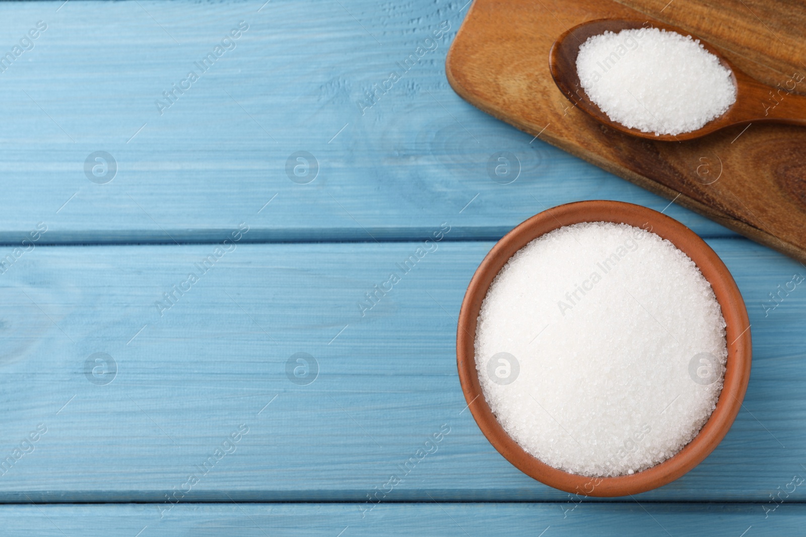 Photo of Granulated sugar on turquoise wooden table, flat lay. Space for text