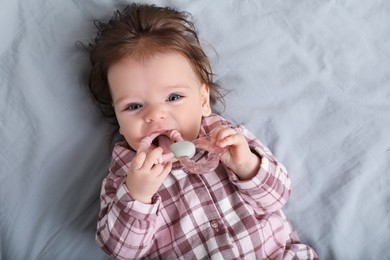 Photo of Cute little baby with toy on bed, top view