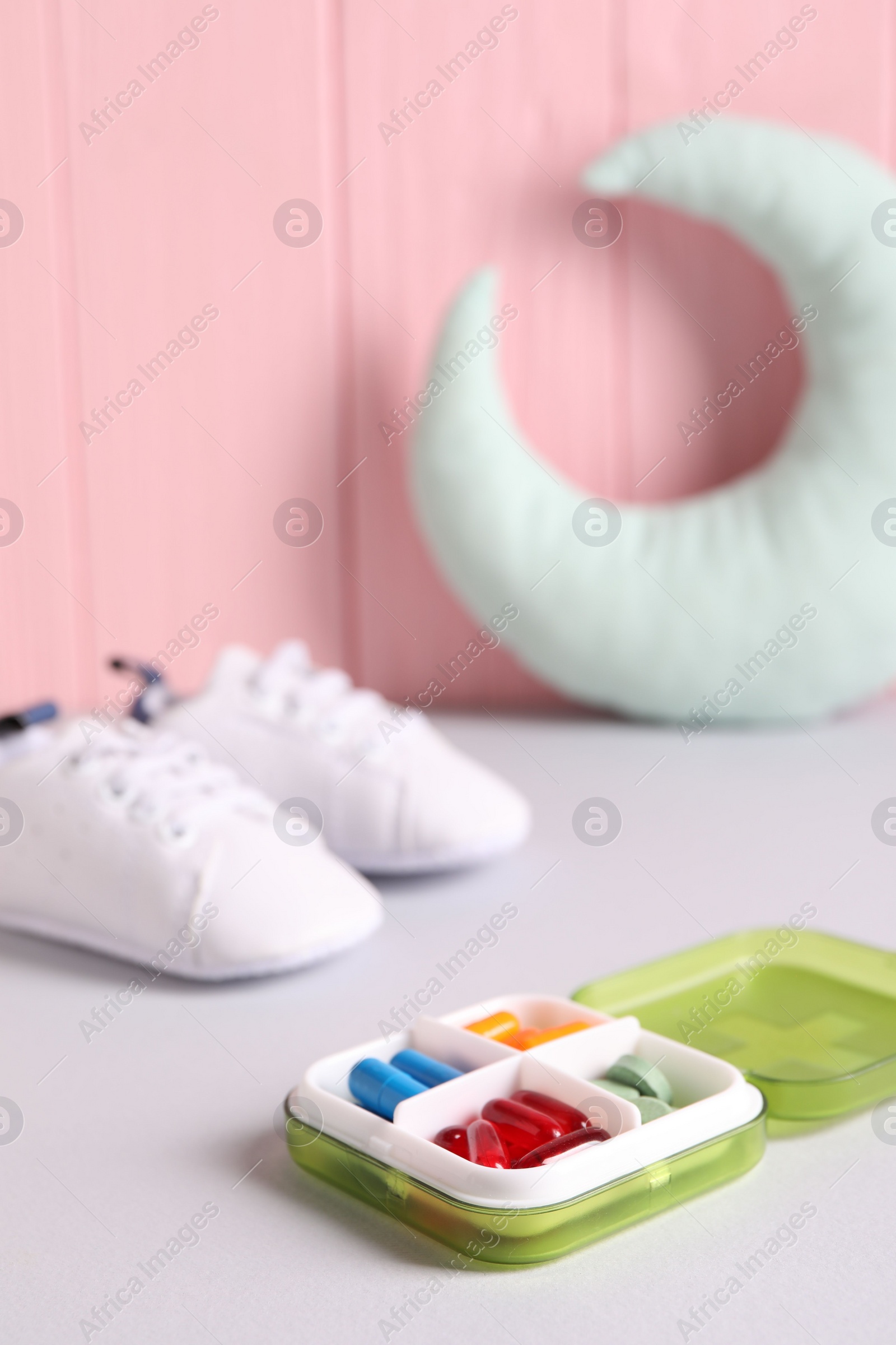 Photo of Different pills in container on grey table, closeup