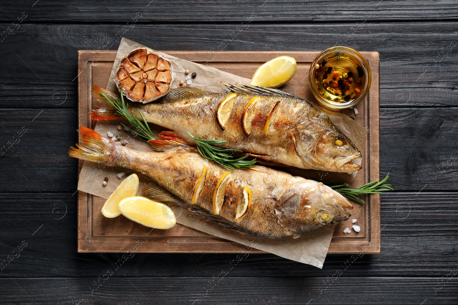 Photo of Tasty homemade roasted perches on black wooden table, top view. River fish