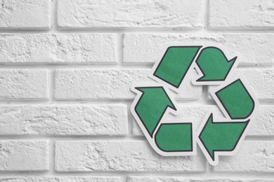 Photo of Paper recycling symbol on brick wall. Space for text