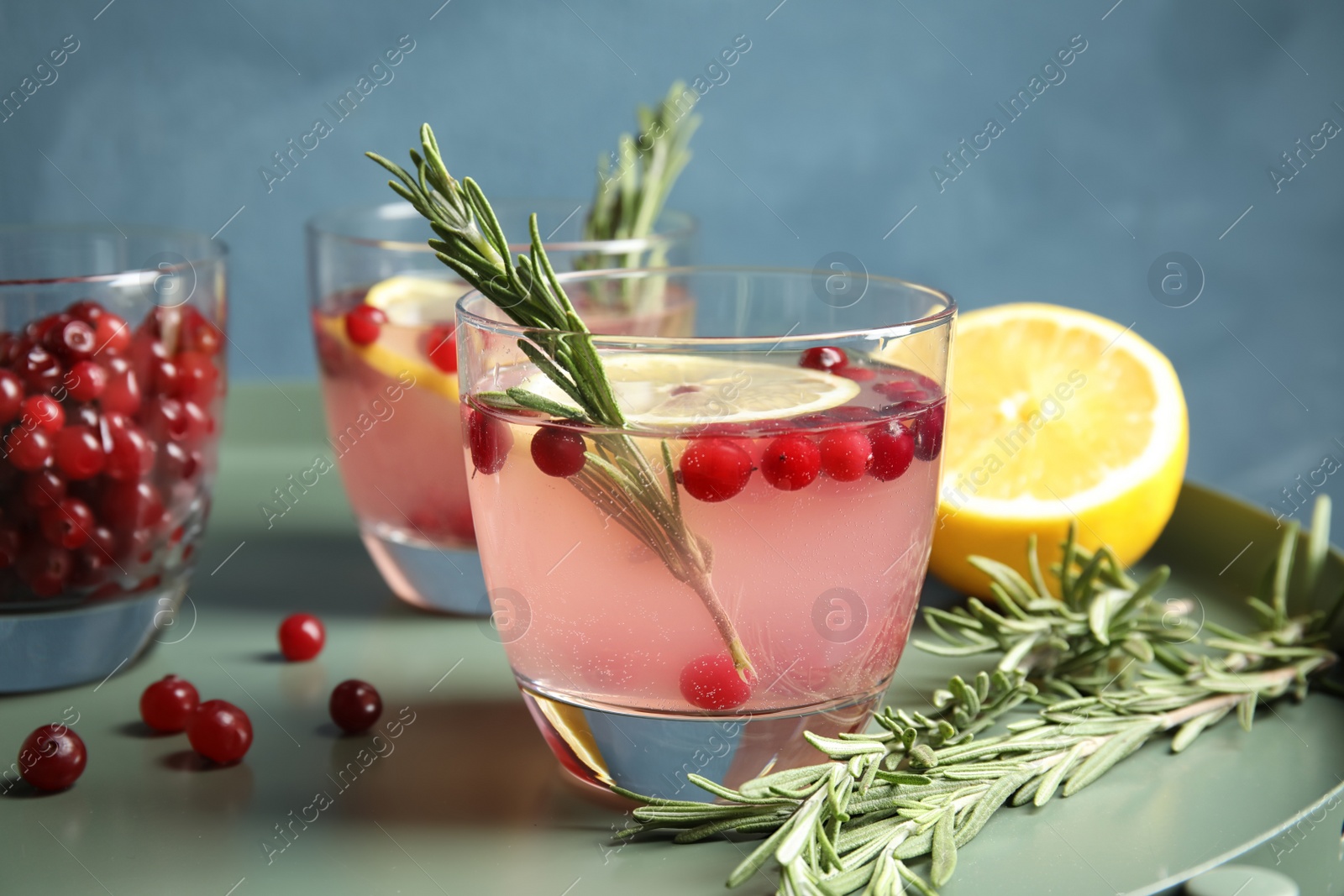 Photo of Tasty refreshing cranberry cocktail with rosemary on table