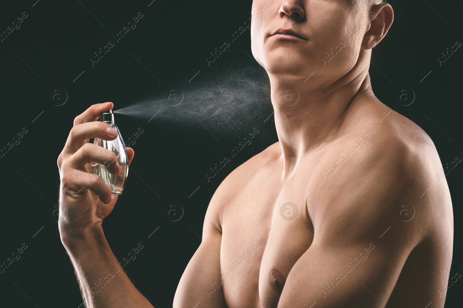 Photo of Handsome man using perfume on black background, closeup