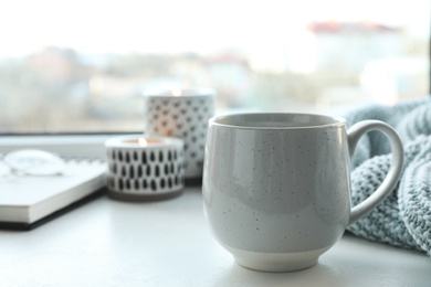 Photo of Cup of delicious hot winter drink on window sill indoors