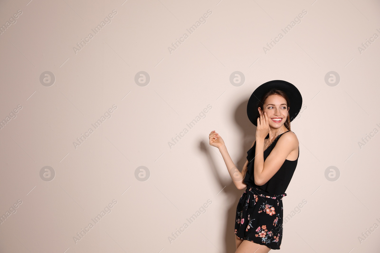 Photo of Young woman wearing floral print shorts and stylish hat on beige background. Space for text