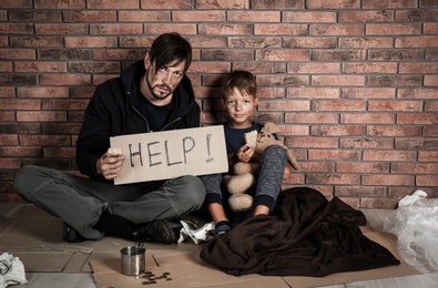 Photo of Poor man with his son asking for help near brick wall