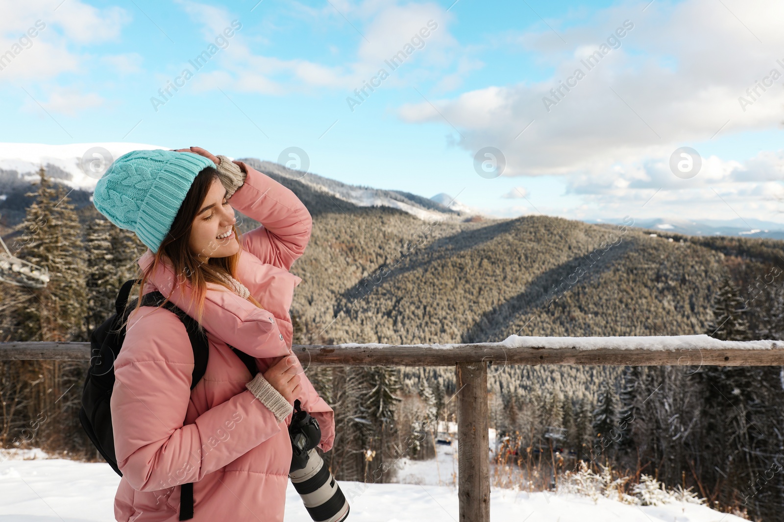 Photo of Young woman with backpack and camera enjoying mountain view during winter vacation. Space for text
