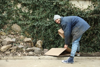 Poor homeless man with cardboard on street