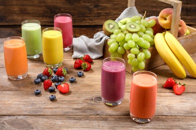 Glasses with different tasty smoothies and ingredients on wooden table