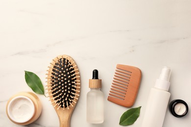Photo of Flat lay composition with wooden hair brush and comb on white marble table, space for text