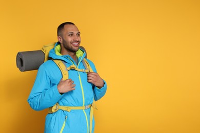 Photo of Happy tourist with backpack on yellow background, space for text