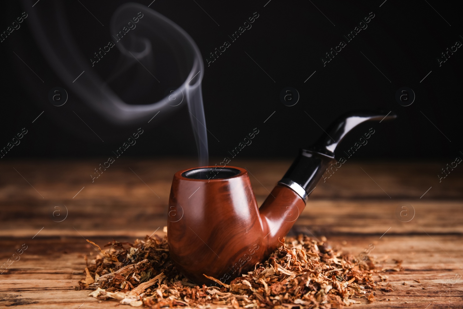 Photo of Smoking pipe with tobacco on wooden table