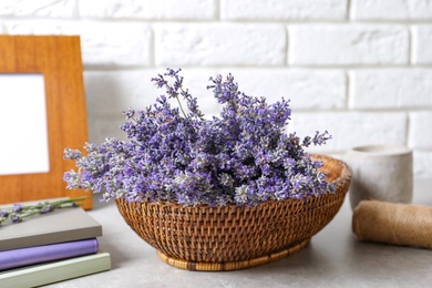 Photo of Composition with basket of fresh lavender flowers on stone table against white brick wall