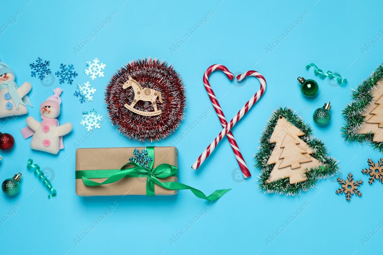 Photo of Tinsel and Christmas decor on light blue background, flat lay