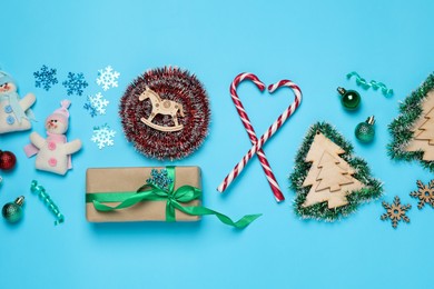 Tinsel and Christmas decor on light blue background, flat lay