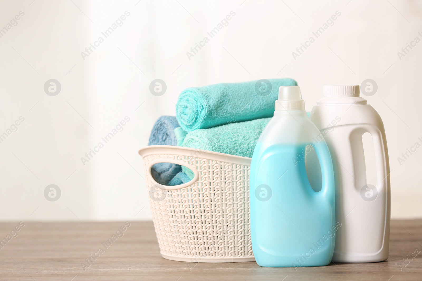 Photo of Basket with clean towels and detergents on table. Space for text