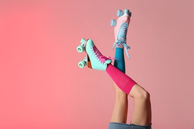 Woman with vintage roller skates on color background, closeup. Space for text