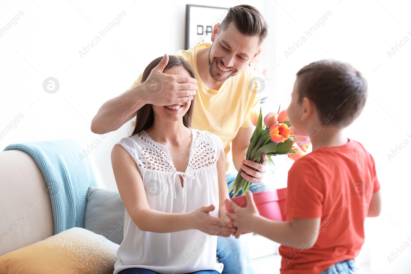 Photo of Happy woman receiving gifts from her husband and son at home. Mother's day celebration