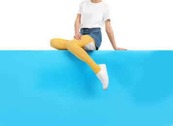 Photo of Woman wearing yellow tights and stylish shoes sitting on color background, closeup