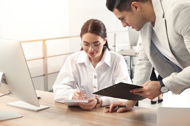 Businessman helping intern with work in office