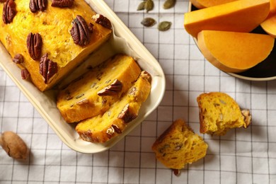 Delicious pumpkin bread with pecan nuts on tablecloth, flat lay