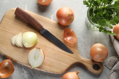 Whole and cut onion on grey textured table, flat lay