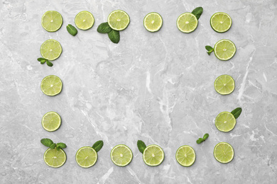 Photo of Flat lay composition with slices of fresh juicy limes on marble table. Space for text