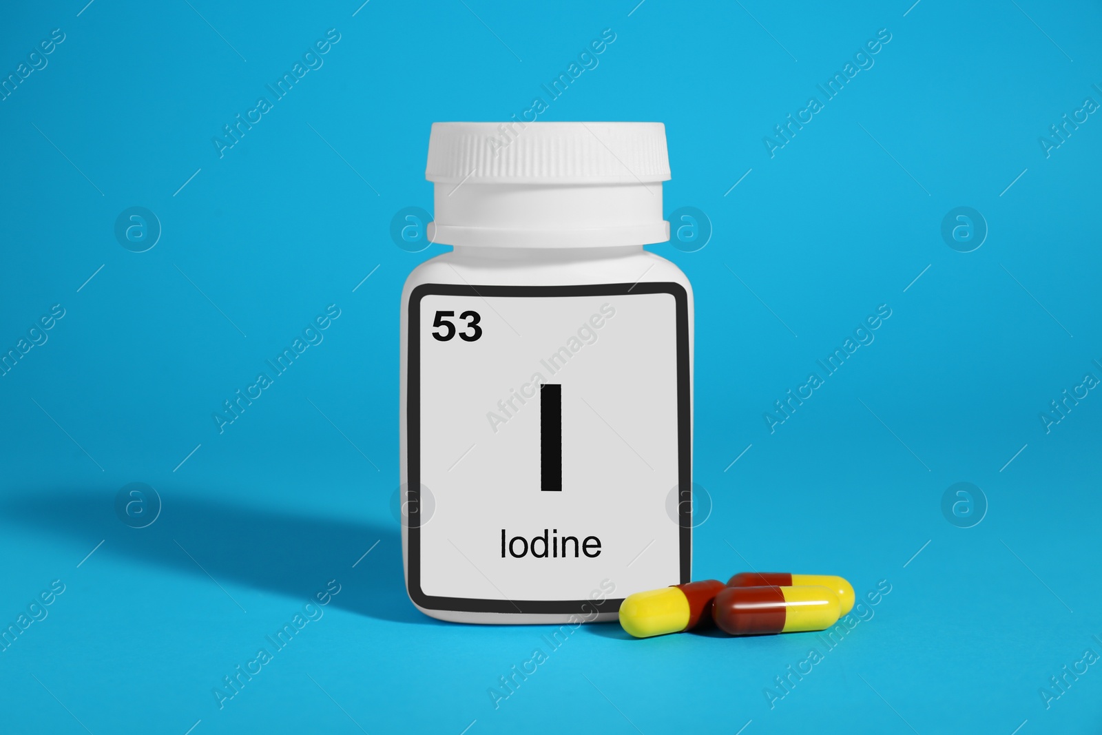 Photo of Bottle of medical iodine and pills on light blue background
