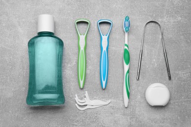 Photo of Tongue cleaners and other oral care products on grey table, flat lay