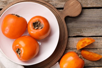 Photo of Delicious ripe persimmons on wooden table, top view