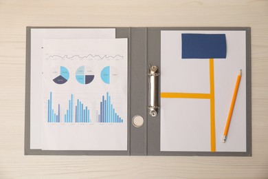 Photo of Business process planning and optimization. Document with different types of graphs and pencil in folder on wooden table, top view
