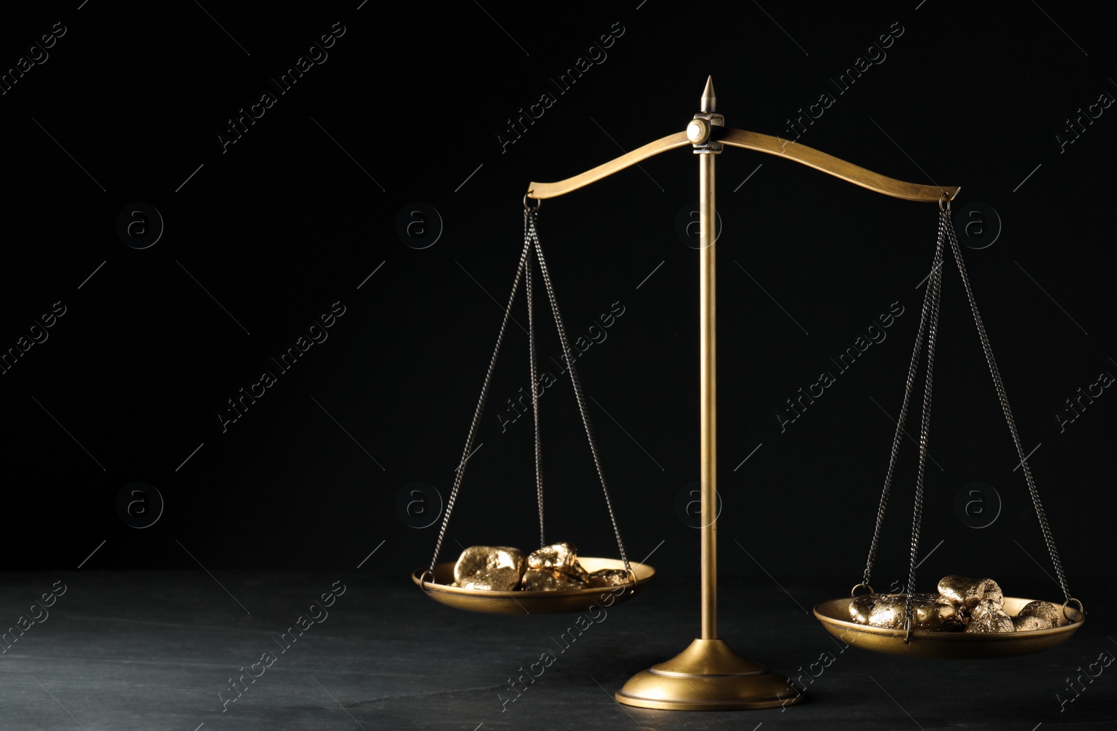 Photo of Vintage scales with gold nuggets on dark table against black background, space for text