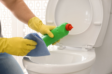 Photo of Man cleaning toilet bowl in bathroom, closeup