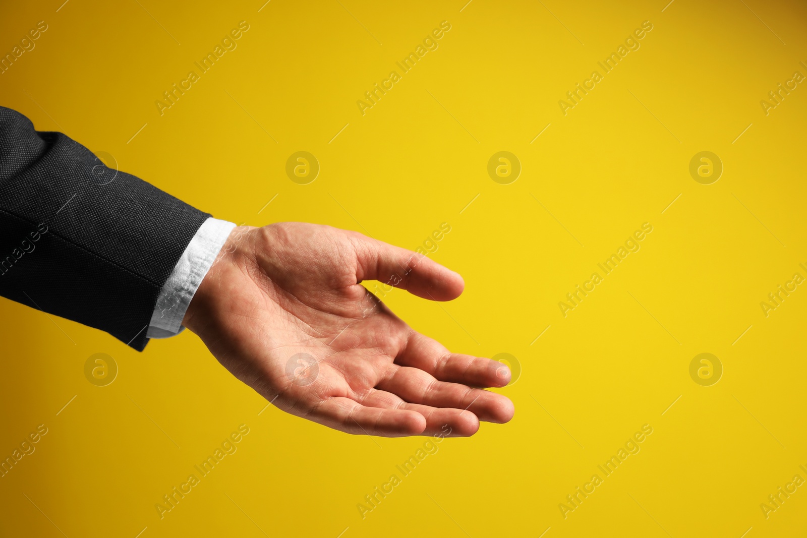 Photo of Man holding something in hand on yellow background, closeup. Space for text