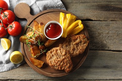 Tasty schnitzels served with potatoes, ketchup and vegetables on wooden table, flat lay
