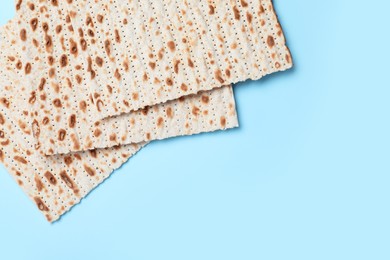 Photo of Traditional matzos on light blue background, flat lay. Space for text