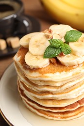 Photo of Tasty pancakes with sliced banana on white plate, closeup